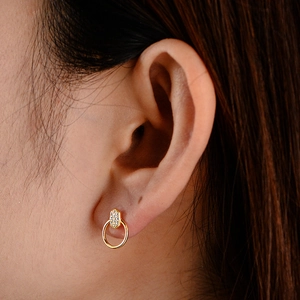 Détail de boucles d'oreilles cercle géométrique avec cristaux pavés sur le lobe d'oreille