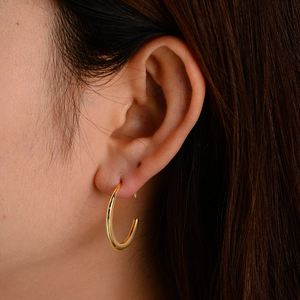Minimalist geometric gold hoop earrings worn on ear showing sleek circular design