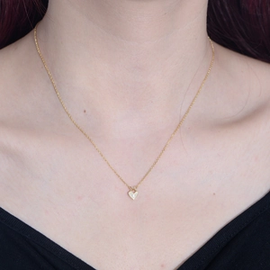 Gold heart pendant necklace with zircon stone on model's neck for a minimalist look
