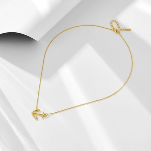 Macro detail of gold S925 sterling silver anchor pendant necklace with minimalist design