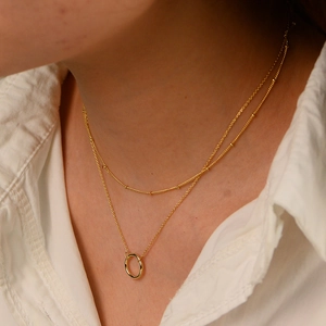 Close-up of double-layer S925 silver necklace with gold beads and circular pendant detail