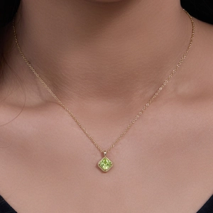 Gold chain necklace featuring a square cut green zircon pendant worn by a model