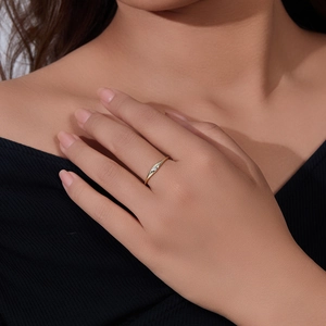 Macro shot of a minimalist gold ring with a single small diamond on a model finger
