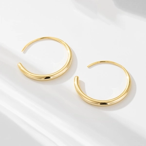 Close-up of 18K gold hoop earrings with gradient thickness on a white background