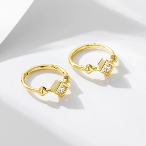 Macro shot of gold square zircon earrings with geometric rivets on white background