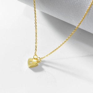 Macro shot of 18K gold heart pendant with round zircon on a delicate cable chain