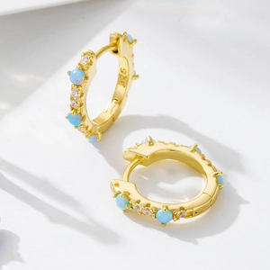 Macro view of gold S925 silver huggie earrings with opal and cubic zirconia stones