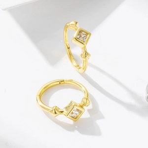 Detail of gold hoop earring with square zircon stone and pyramid stud accents
