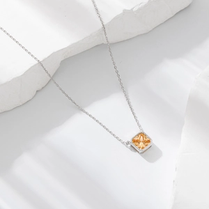 Detail of S925 silver necklace featuring a square yellow zircon pendant on stone background