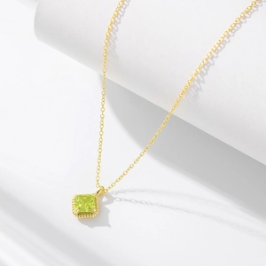 Macro view of gold chain with square green zircon pendant and twisted rope texture edge
