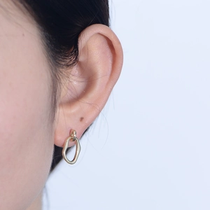 Close-up of a gold irregular geometric drop earring with polished finish on model