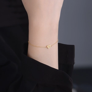 Detailed view of a gold heart-shaped charm bracelet worn elegantly on a female wrist