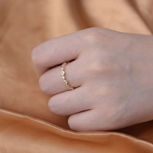 Elegant gold geometric ring with round and square zircon stones on champagne satin background
