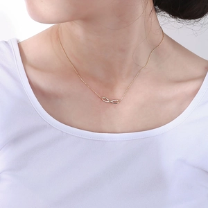 Close-up of golden infinity pendant necklace with micro-pave crystals on a female model