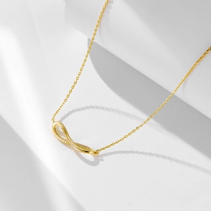 Macro shot of gold infinity pendant with pave zircons on a delicate O-link chain