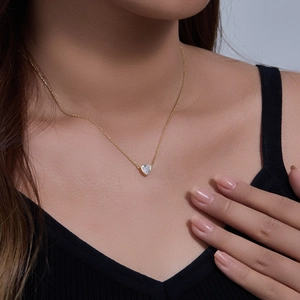 Close-up of elegant gold heart pendant necklace with sparkling zircon on model neck