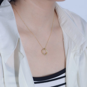 Détail d'un collier carré géométrique doré avec zircons porté par un mannequin femme