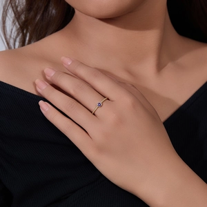 Detail of twisted gold ring with round purple amethyst worn by a model against black clothing