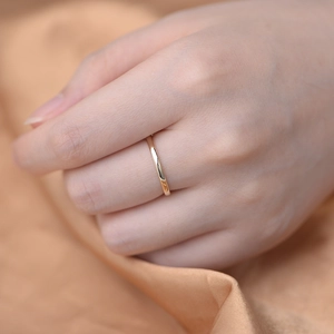 Dettaglio di un anello minimalista dorato indossato su sfondo di tessuto di seta