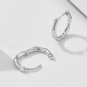Détail macro de boucles d'oreilles vagues argentées avec finition miroir polie