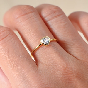 Close-up of minimalist gold ring featuring a triangle-cut diamond on a slender band