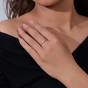 Close-up of a s925 silver gold-plated twisted band ring with pavé diamonds on a finger