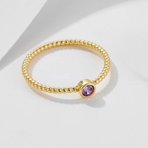 Macro view of gold rope band ring featuring a round purple amethyst bezel setting