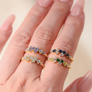 Macro shot of gold silver rings with colorful zircon inlay stacked on fingers