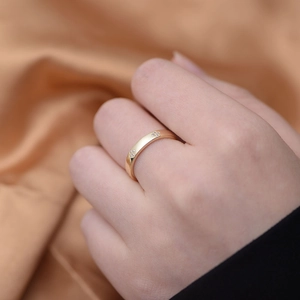 Detail of gold four-leaf clover ring with diamonds worn on hand over silk fabric