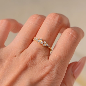 Macro shot of minimalist gold ring with nine white round-cut crystals on finger