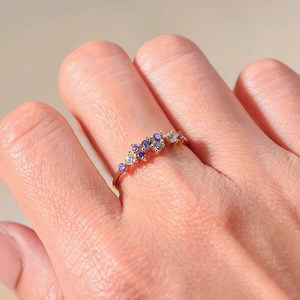 Macro shot of 18K gold ring featuring colorful purple and clear gemstones in a wavy pattern