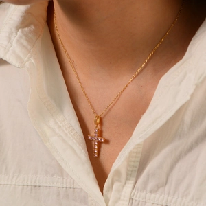 Gros plan d'un collier croix doré avec zircons roses porté par un mannequin