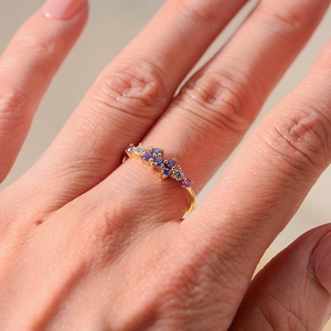 Detail of minimalist gold silver ring with purple and white round-cut crystals