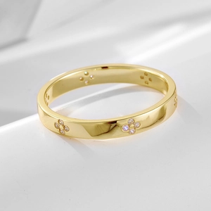Minimalist gold four-leaf clover ring with sparkling zircons on white background