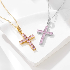 Colliers croix en zircon rose en finitions or et argent sur un socle en pierre blanche