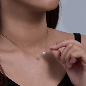 Detail of square light blue topaz pendant on minimalist gold chain necklace on neck