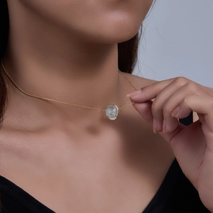 Close-up of aquamarine oval pendant in gold finish worn on female neck
