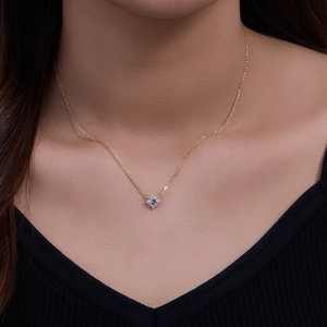 Elegant gold necklace with floral pendant featuring blue gemstone and zircon on a model