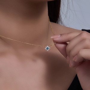 Close-up of a s925 silver flower pendant with a blue sapphire zircon on a model neck