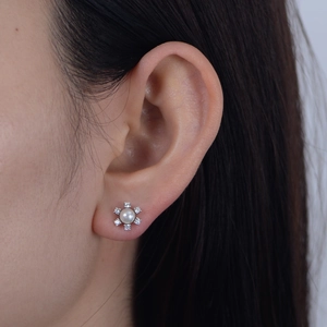Detail shot of s925 silver snowflake earrings with round pearl and zircon studs on ear