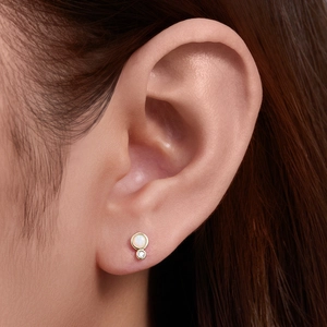 Detail of gold-plated 925 silver stud with white opal and round zircon in a bezel setting