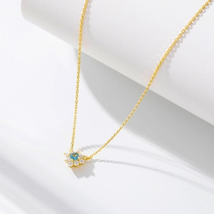 Detail of gold floral necklace with blue center stone and white cubic zirconia petals
