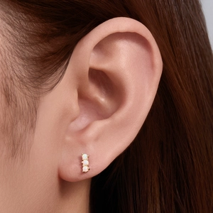 Close-up of 925 sterling silver ear stud featuring three white opal stones on the ear lobe