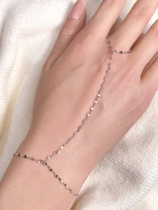 Detail of a sparkling 925 silver hand chain featuring a sequin link bracelet and ring