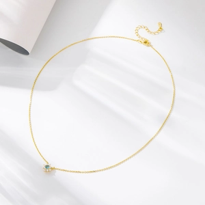 Detailed view of gold flower pendant with blue zircon center and adjustable necklace chain