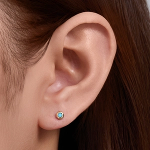 Close-up of a 925 silver stud earring with turquoise stone on earlobe