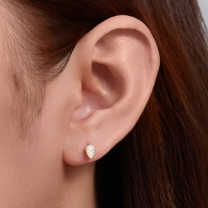 Close-up of teardrop 925 silver stud earring with opal and gold beaded edge on ear
