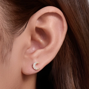 Close-up of a 925 silver crescent moon stud earring with gold plating and white zircons