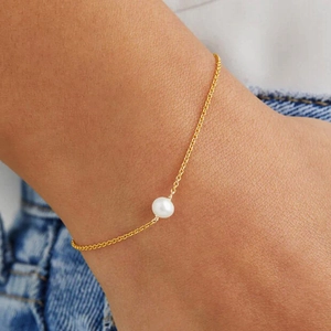 Close-up of minimalist S925 silver gold-plated bracelet featuring a natural white pearl