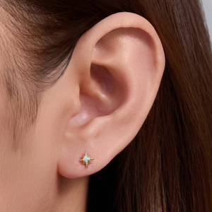 Close-up of 925 sterling silver gold star stud earring with opal inlay on ear